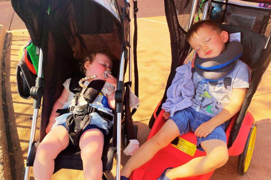 2 kids napping in stroller traveling-with-kids