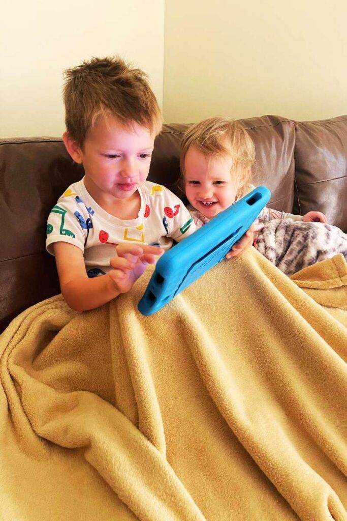 two kids looking at tablet traveling-with-kids