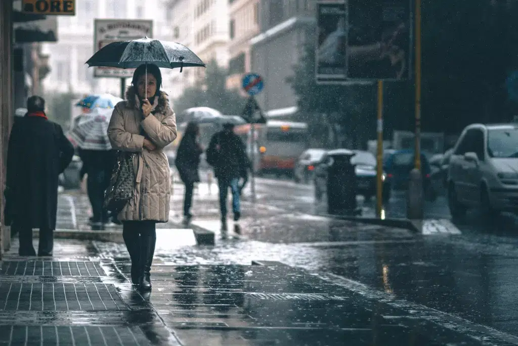 Woman walking in the rain in ROme.  She has an umbrella and a heavy coat