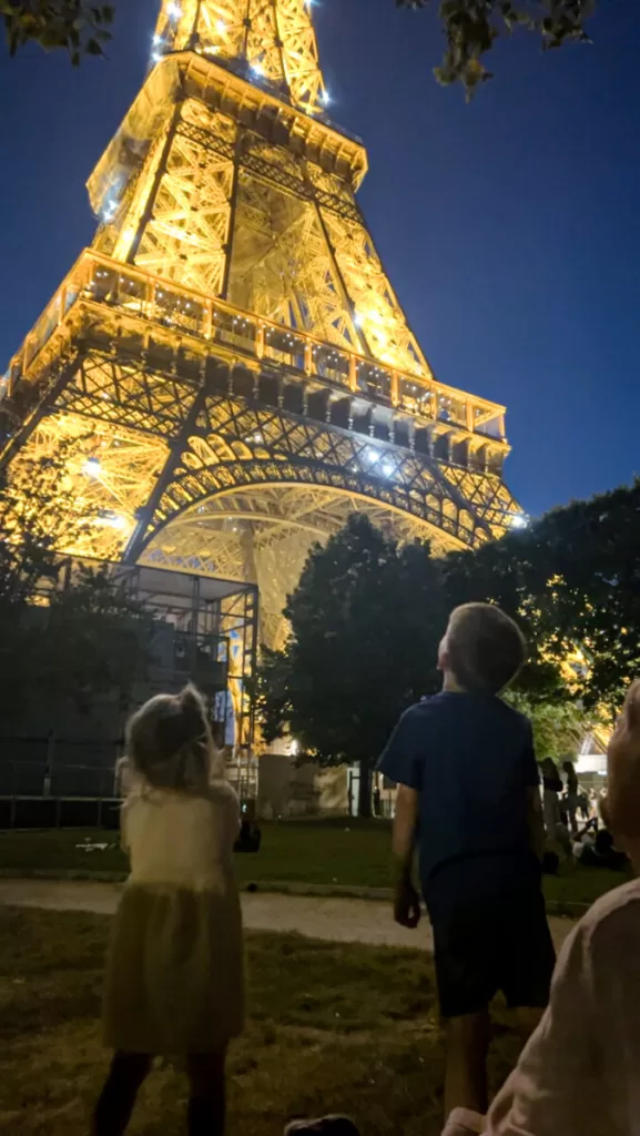 Twi kids staring up at the Eiffel tower at night.  Paris with kids in winter