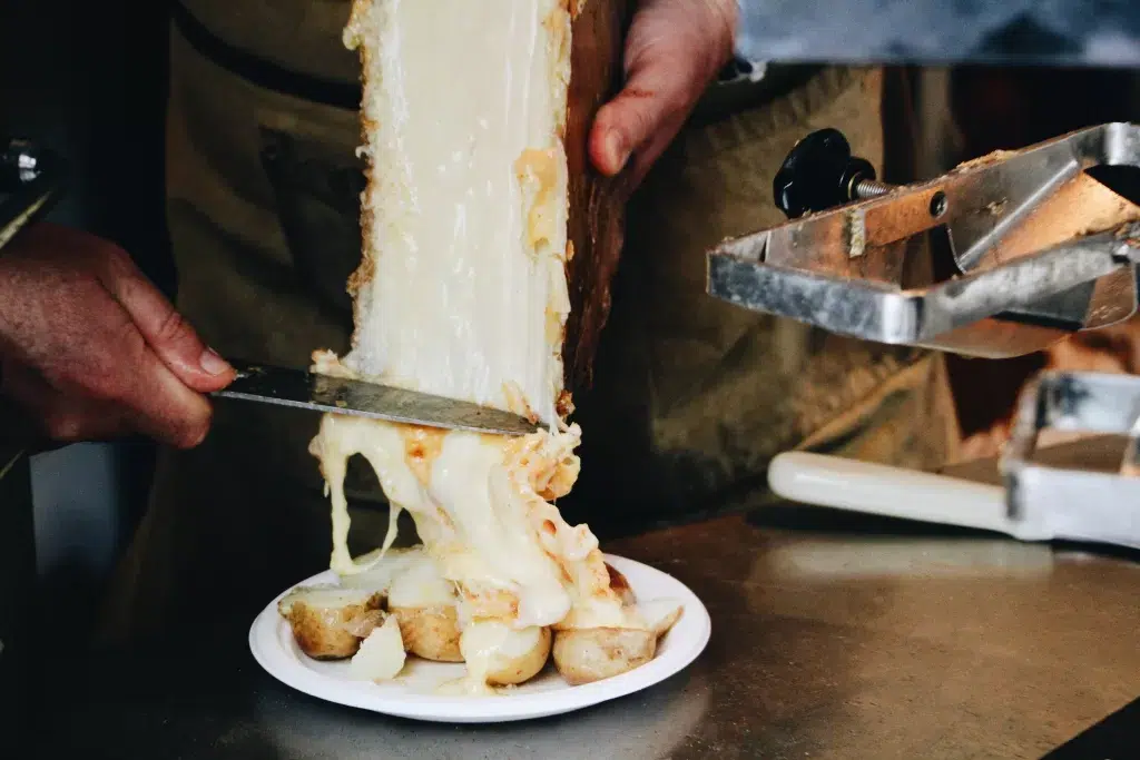 Melted cheese being served on top of potatoes