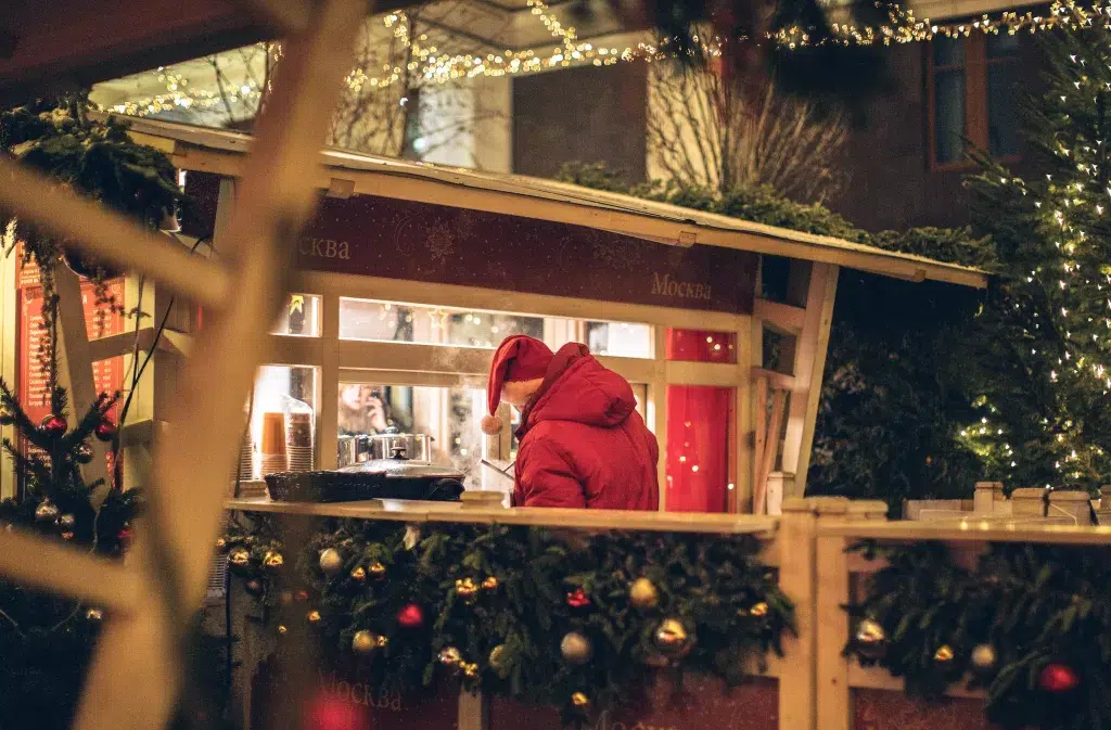 Stall at Chistmas market in Paris.  Man is buying goods from this vendor while holiday decorations surround the vendor