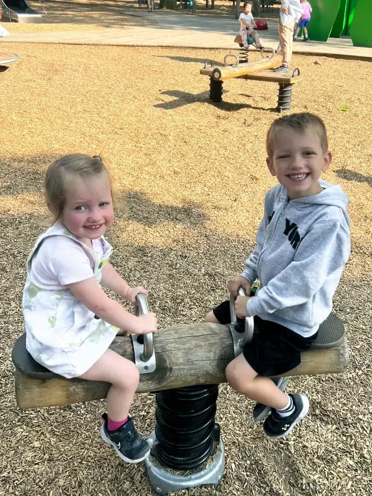 Two kids playing on playground sea saw. 