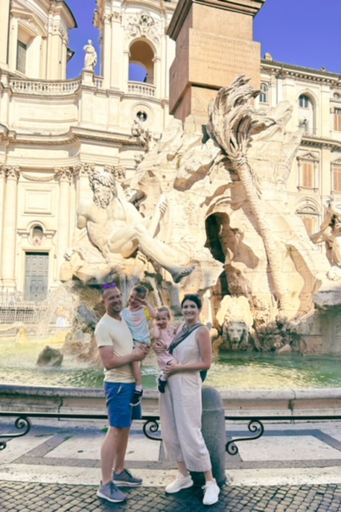 Family standing in front of large fountain in Rome.