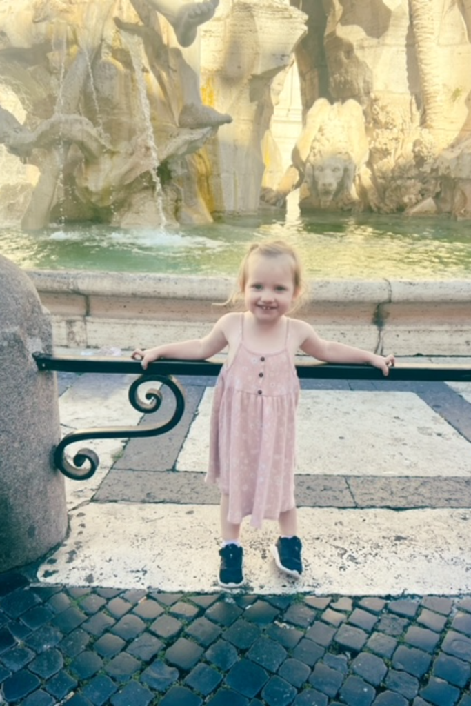 Toddler standing in front of the Trevi Fountain in Rome. 