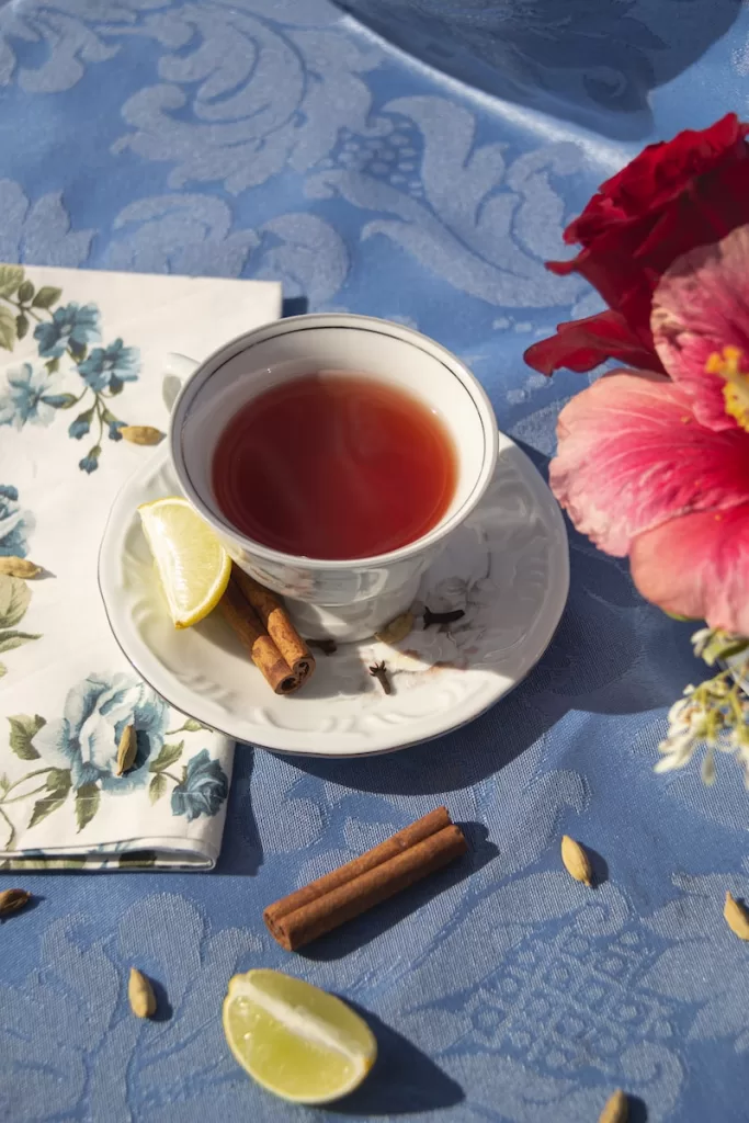 a cup of tea next to a napkin and a flower