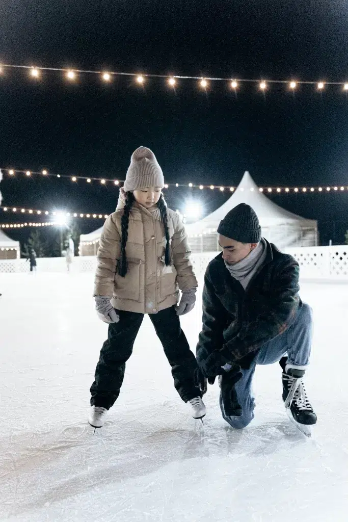 Father and daughter ice skating in Paris under christmas lights