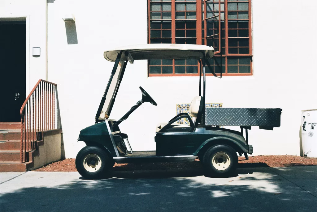 Green and white golf cart parked.  Rome golf cart tours