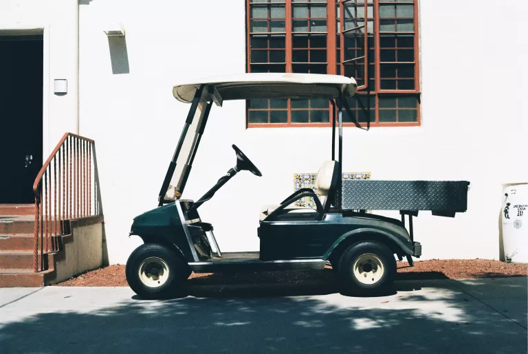 Green and white golf cart parked. Rome golf cart tours