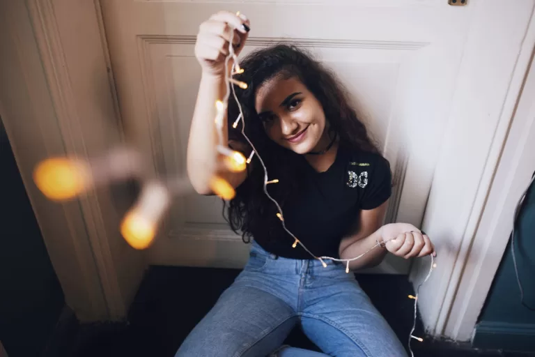 Cheerful young woman with light garland