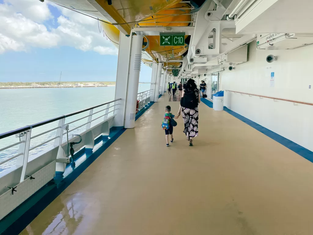 Mother and child walking on a cruise ship deck holding hands