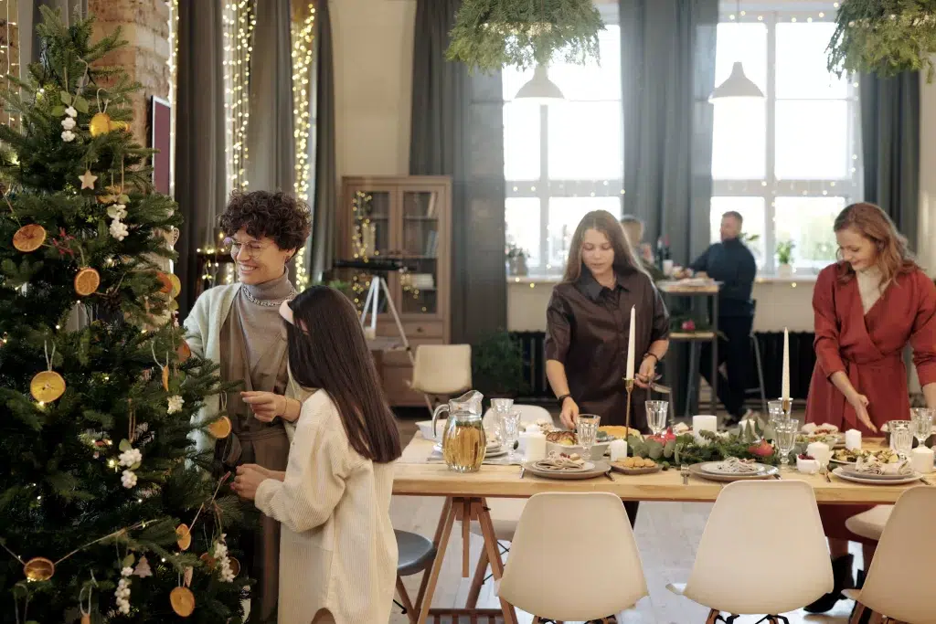 Family at Christmas.  4 young teenagers gathered around a table with Christmas tree in for ground