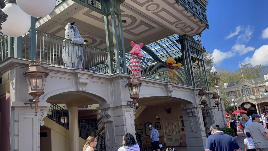 Piglet, WInnie the Pooh and Eeyore standing on a balcony waving to crowd at Disney World