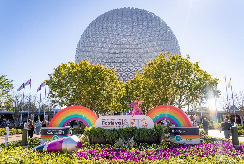 Epcot's famous ball with rainbows in front of it. Epcot's festival of the arts with kids