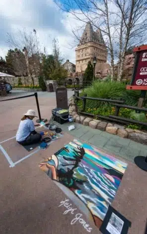 Women sitting on pavement making chalk art