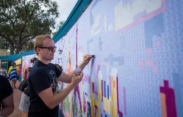 Large mural with man in sunglasses painting part of it. 