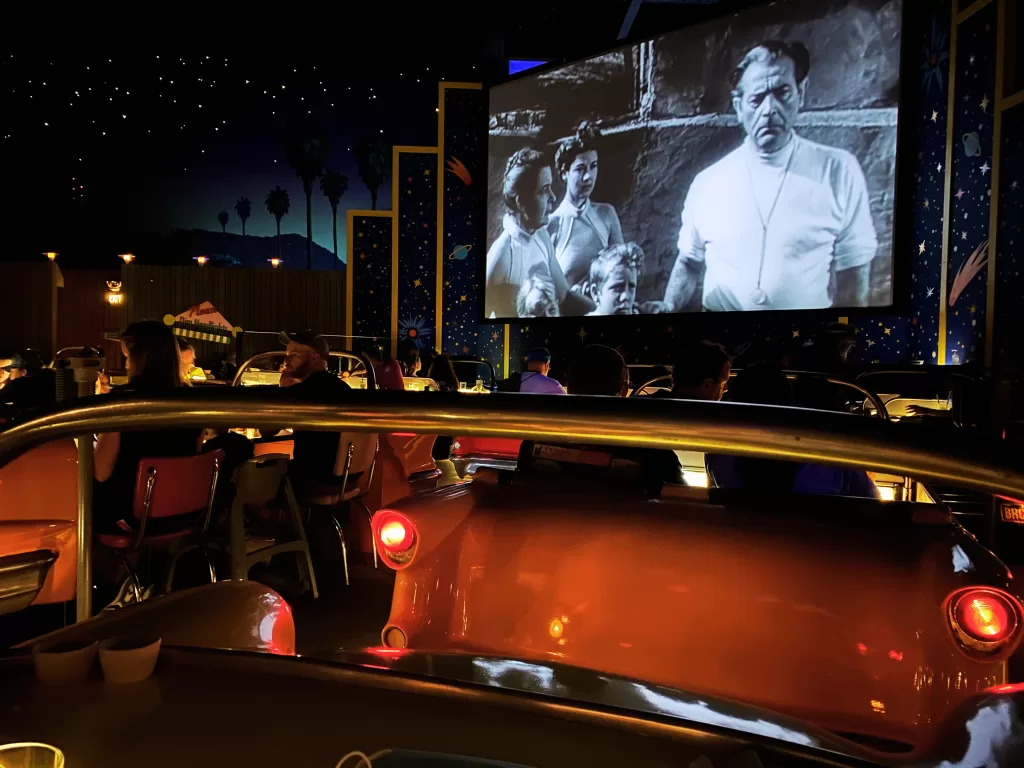 Giant drive in movie screen inside a restaurant at disney world. Showing a black and white movie