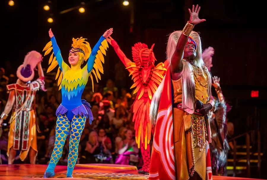 Performers at Disney's Animal Kingdom during the lion king show,  Performers are wearing colorful outfits with feathers