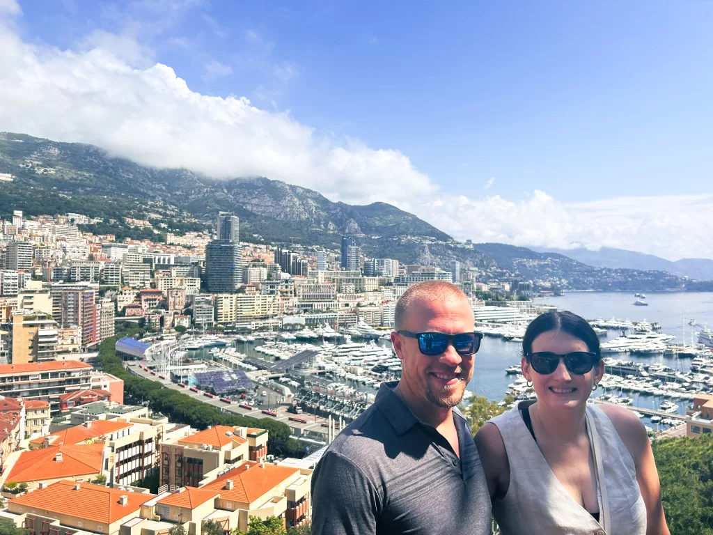 Man and woman standing with a view of the port of monte carlo, monaco behind them