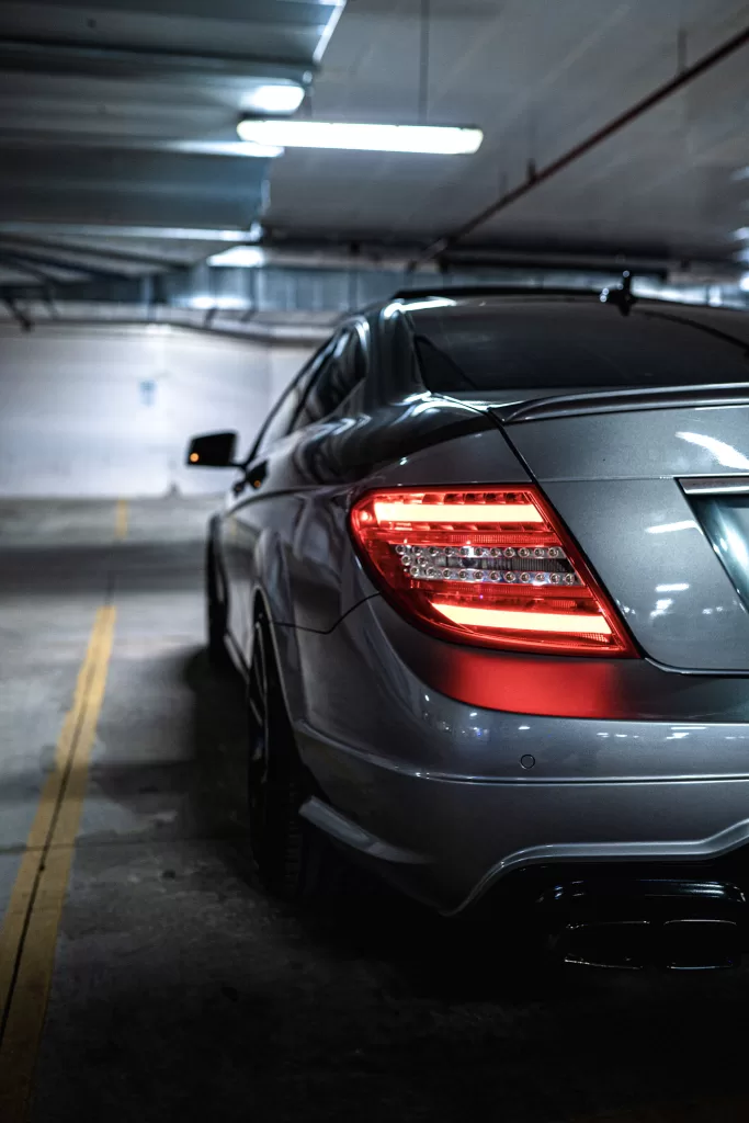 Back left tail light of silver sedan car sitting in a parking garage. 