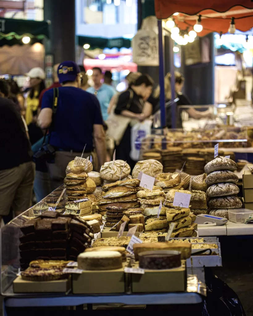 Cheese shop with stacks of cheese sitting in the stall at large open air market. Borough Market, London