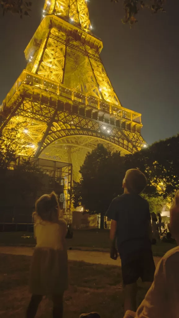 two kids looking at the eiffel tower lit up at night. Paris with kids in spring