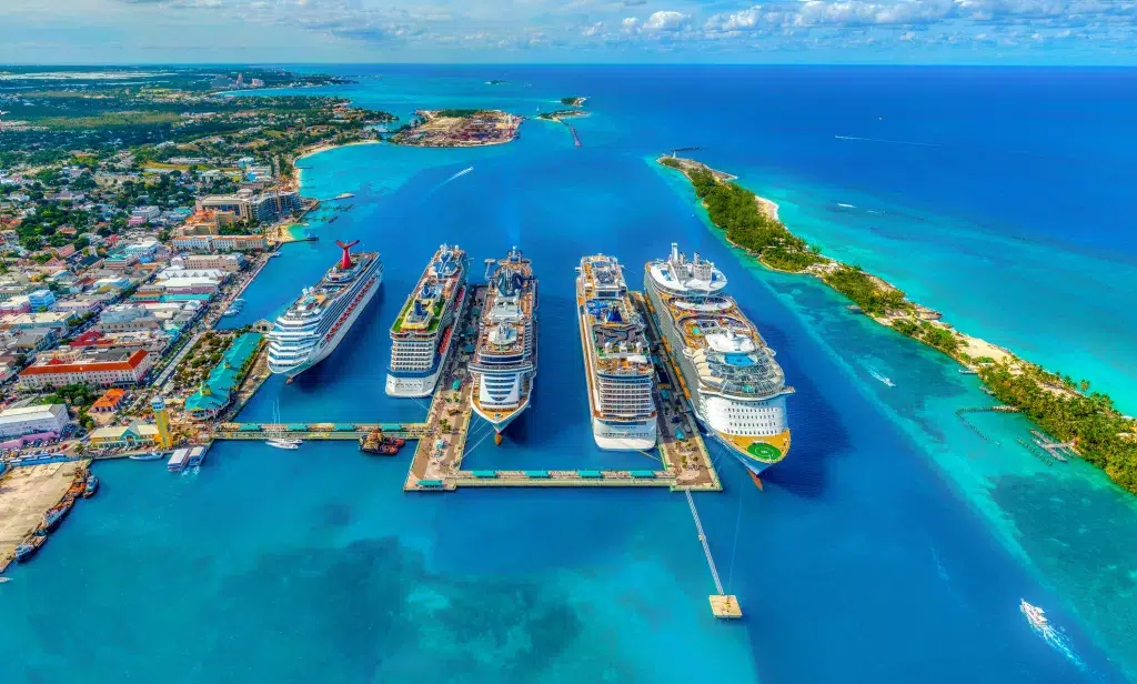 4 large cruise ships lined up in a port and taken from an aerial view.   the ocean is very blue