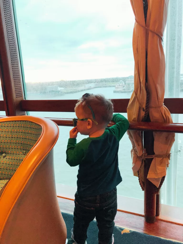 Toddler with sunglasses on looking out on the ocean of a cruise ship