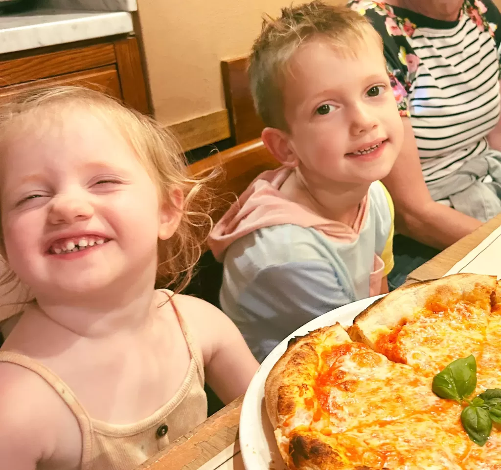 Boy and girl sitting in front of an italian pizza in Rome.  Places to visit in italy with children