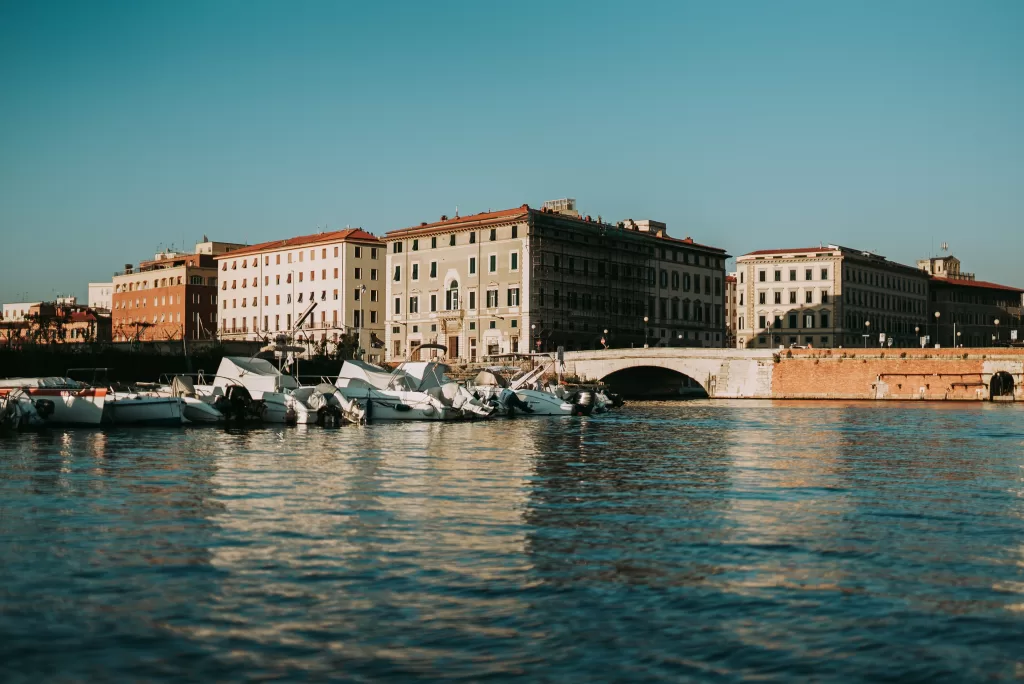 Two tan buildings along the waterway harbor in Livorno