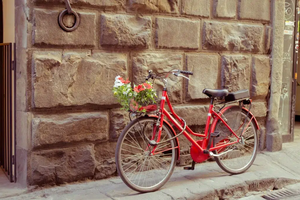 red bike leaning on stone wall in italy