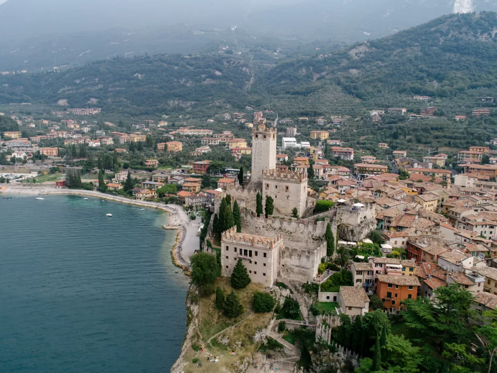 Large lake in Italy(Lake Garda). Blue water with smalll town on the coast. There is a bell tower in the center of town.