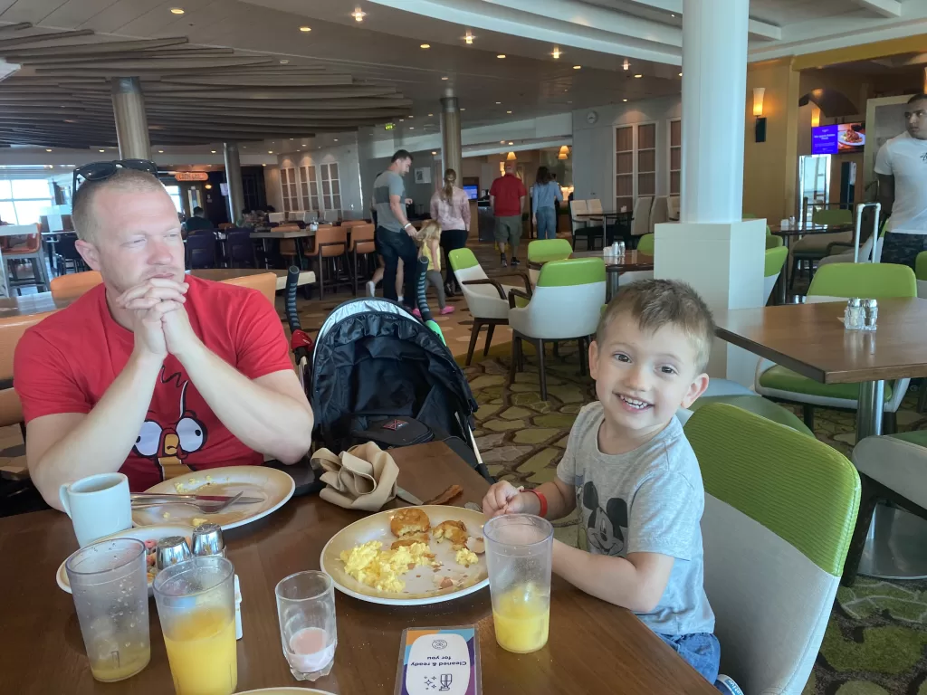 Small child sitting at a table eating buffet food. This article is addressing what food is free on navigator of the seas.