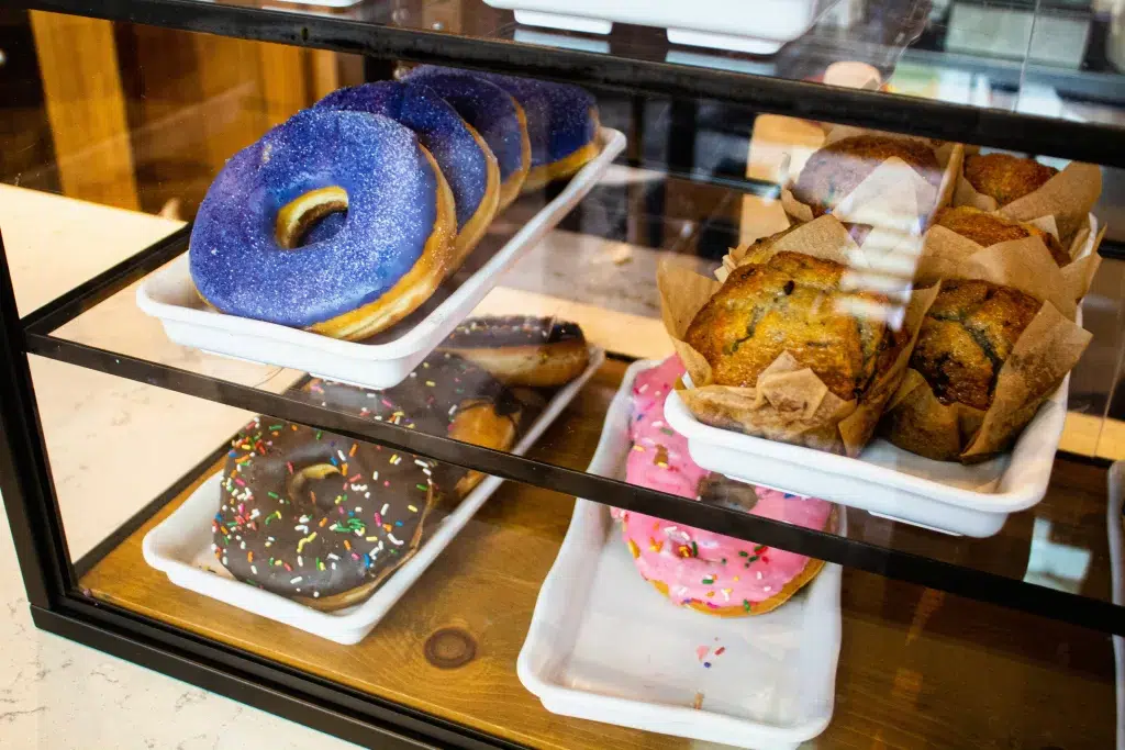 Array of pastries in case including a blue donut and a pink donut with sprinkles at Joffreys coffee cart at Disney world's epcot.