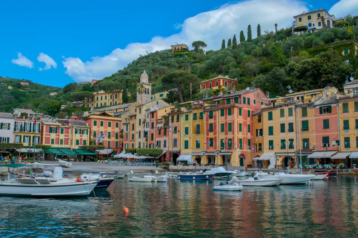 is portofino on amalfi coast. coastline and harbor with white boats along a row of yellow and pink buidlings in italy.