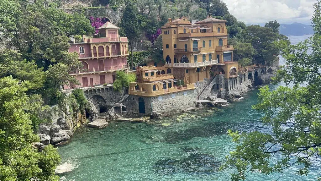 Blue lagoon with houses on side of cliff in italy. Houses are yellow and pink