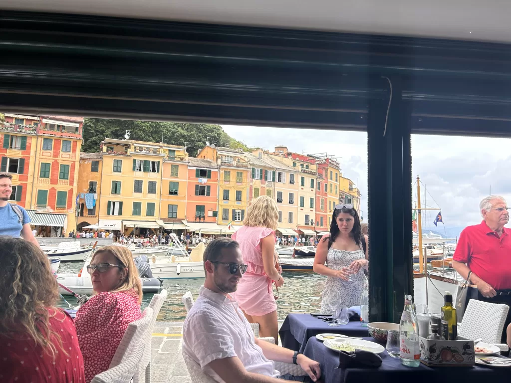 patrons sitting down for lunch in Portofino italy. in the background, there are colorful buildings.