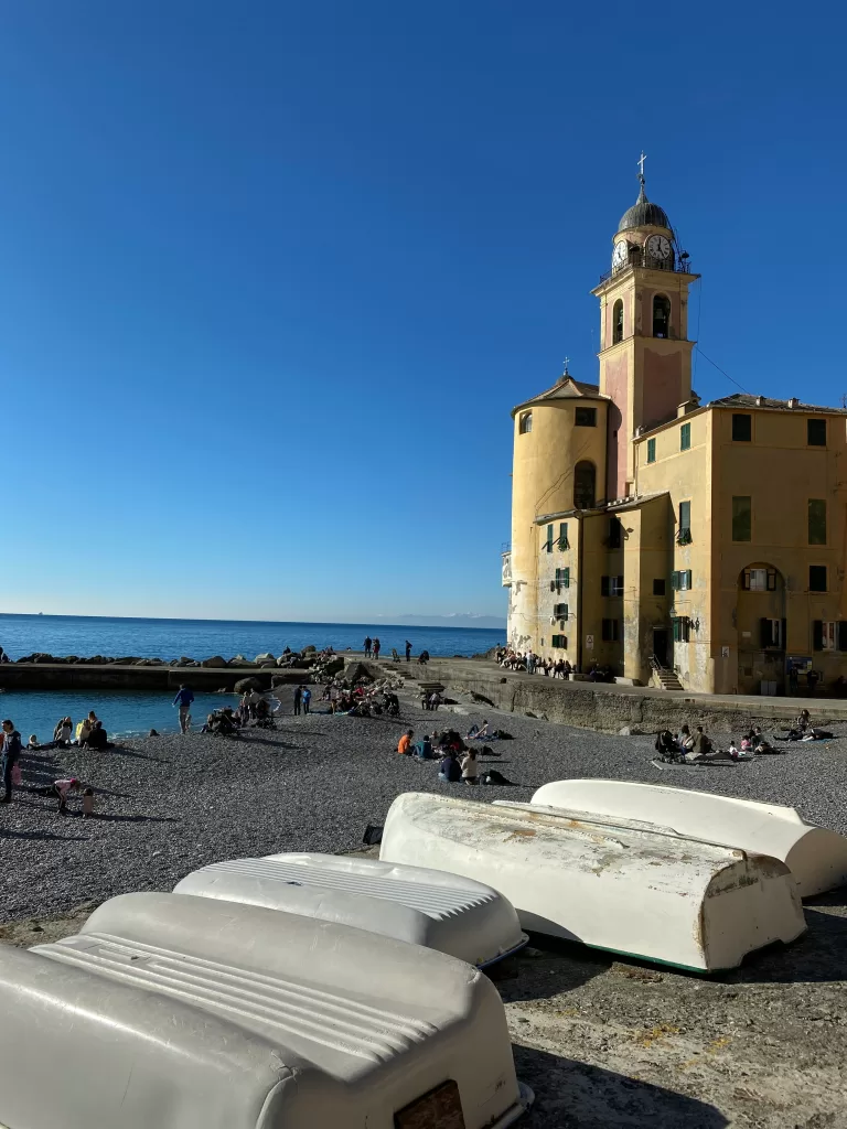 Yellow tower at the forefront of a rocky beach in Camogli italy. public beaches in portofino.