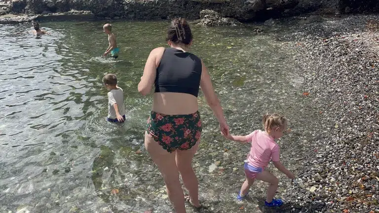 mom and child play on rocky beach in italy.