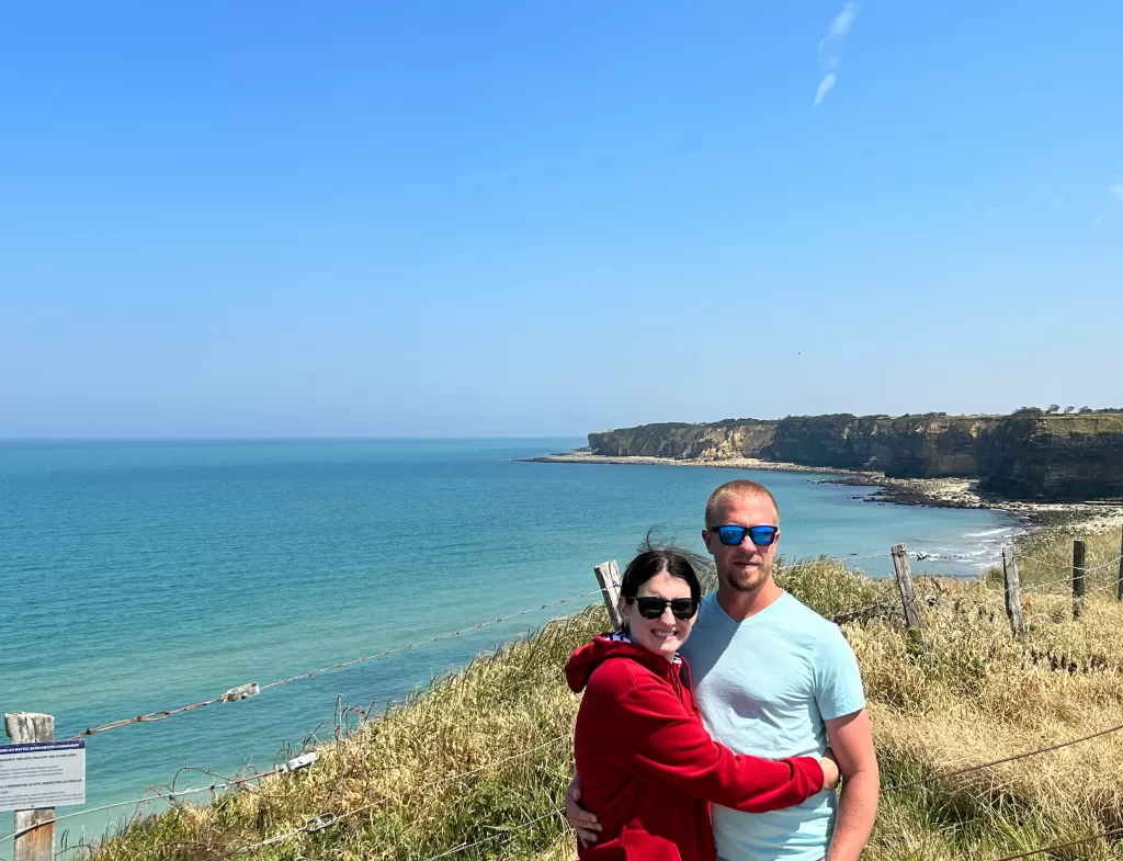 Two people standing in front of the beaches in Normandy.