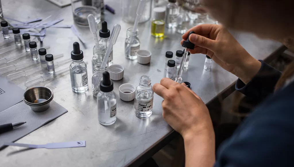person making perfume by squeezing different scents into bottles