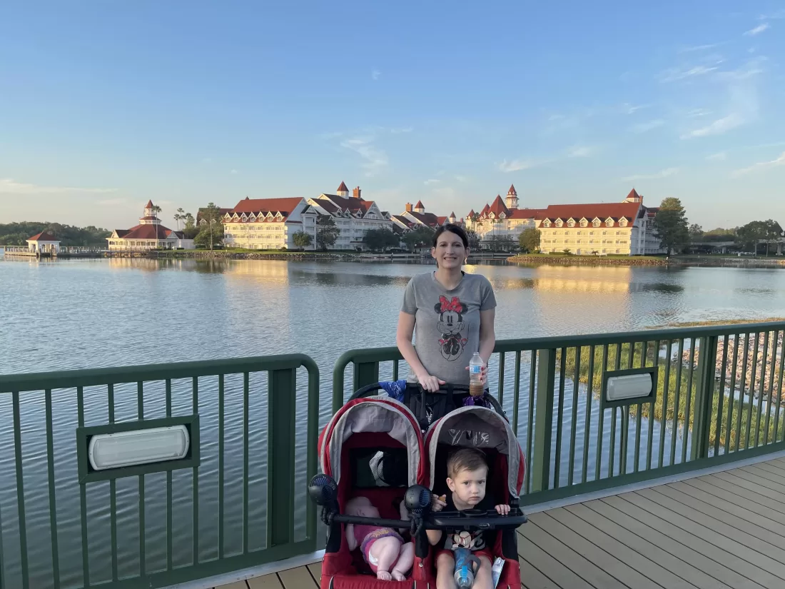 Mom in a mickey mouse shirt standing in front of the grand floridian resort with stroller and two kids. Grand Floridian with kids
