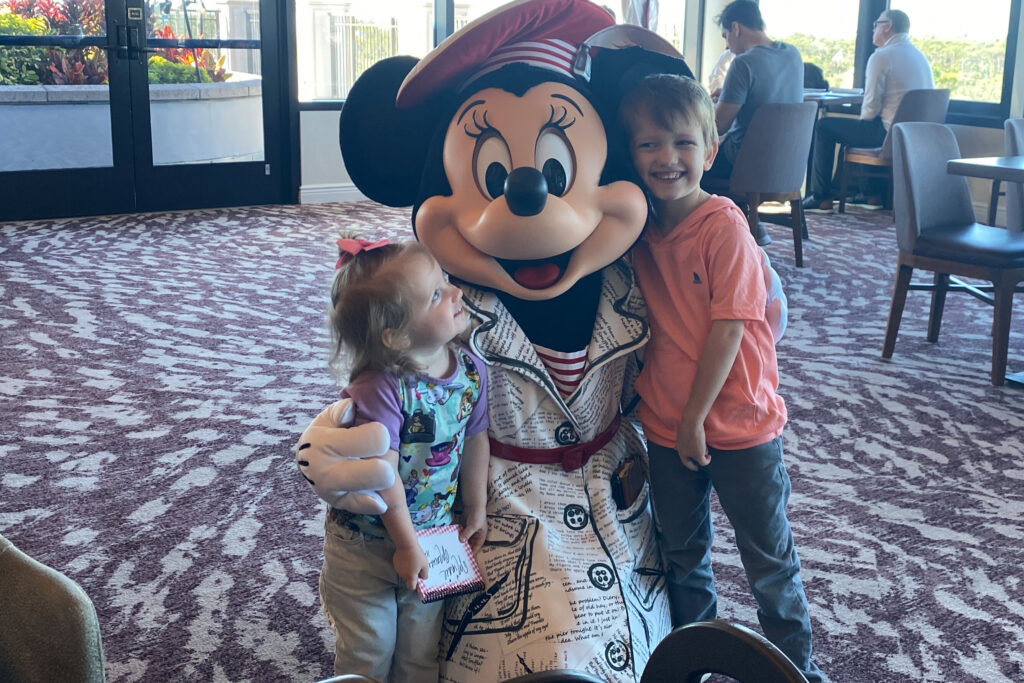 Two small kids posing with the character Minnie Mouse