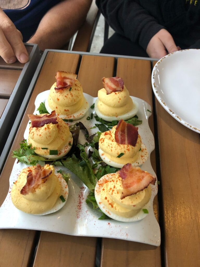 6 deviled eggs topped with bacon and parsley