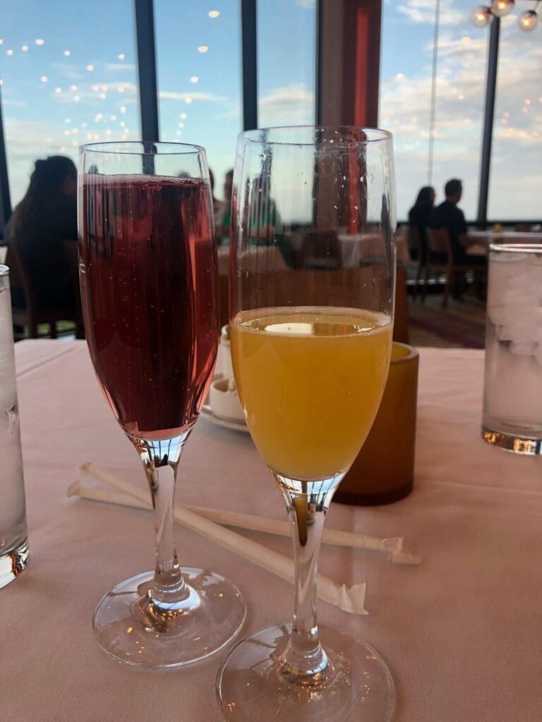 Two flutes of beverages.  One appears to be wine, the other appears to be a mimosa