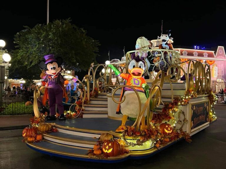 Parade float that is lit up with twinkle lights during the halloween parade at disney. donald and mickey are riding on the float