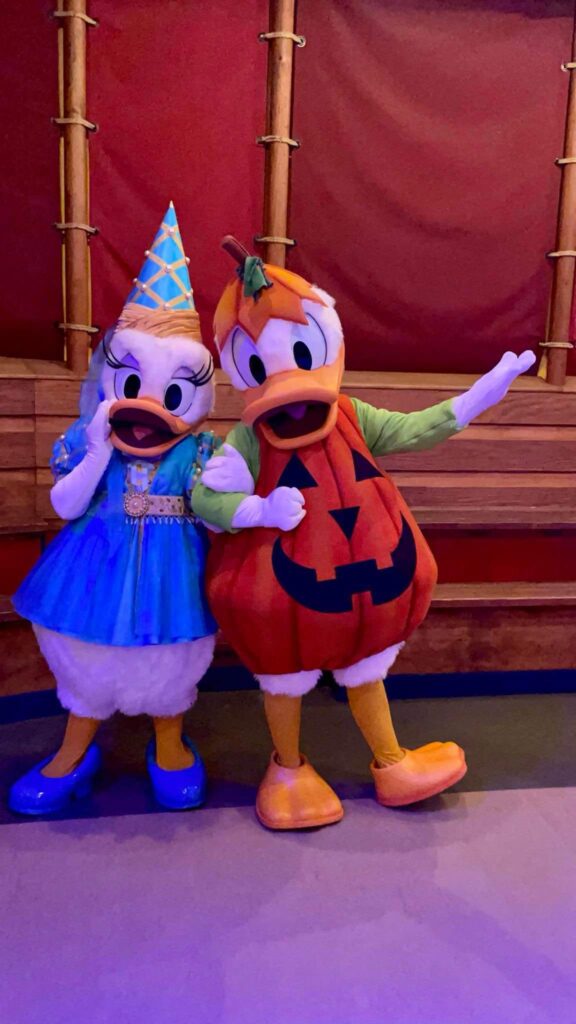 Disney's Donald and Daisy Duck dressed in their halloween costumes.  donald is a pumpkin and daisy is a princess