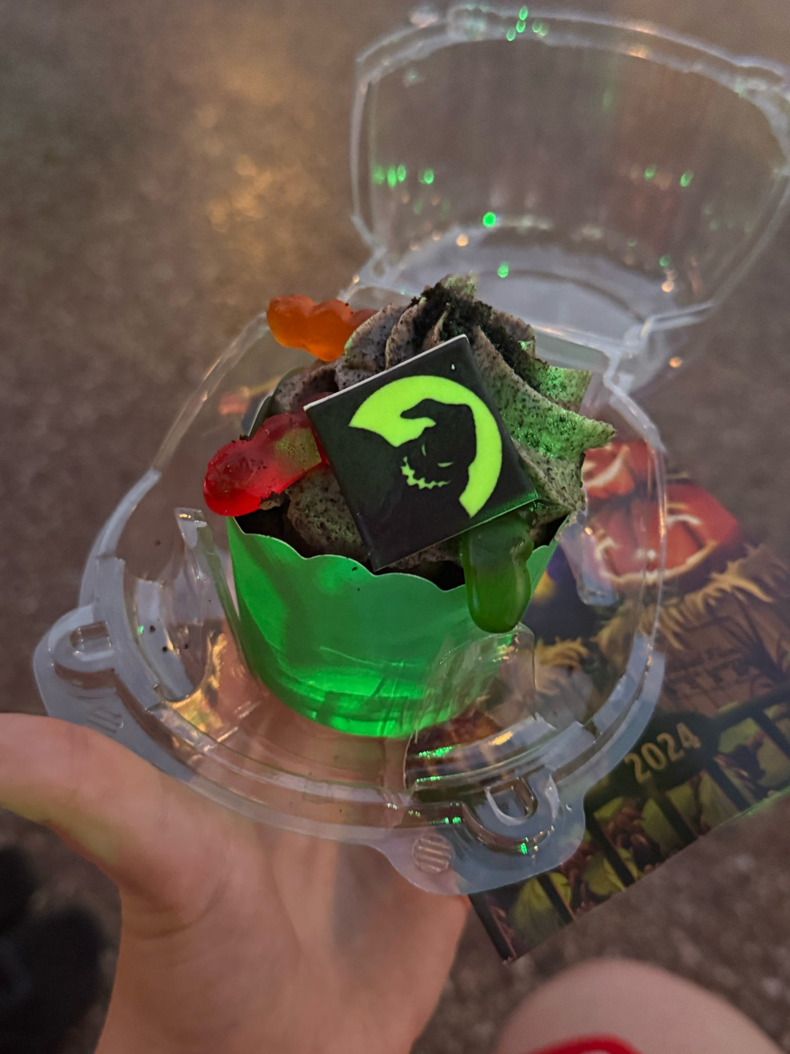Cupcake with green frosting and gummy worms on top