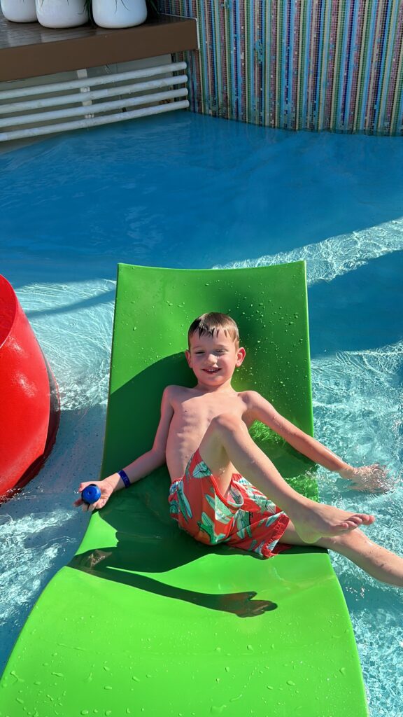 Little boy sitting on on a green pool deck chair