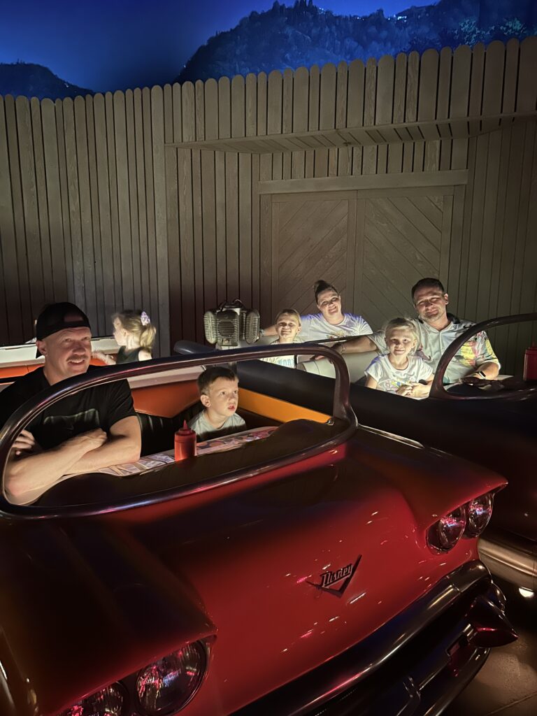 family sitiing in vintage cars at a restaurant at disney world